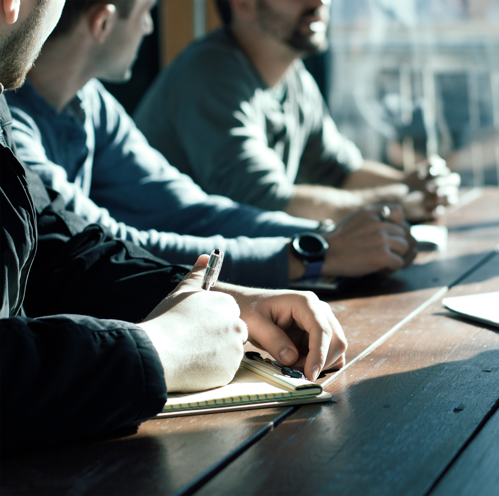 Company Culture Employees sitting at a wood take for a meeting, about us