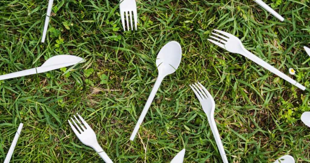 plastic cutlery scattered across green grass