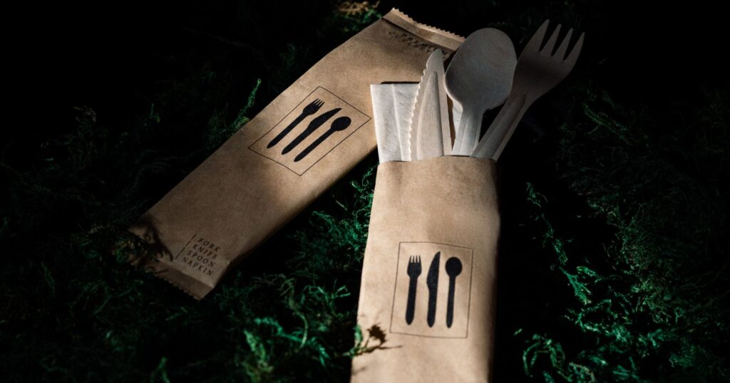 sustainable products wood cutlery in compostable paper packaging on bed of moss