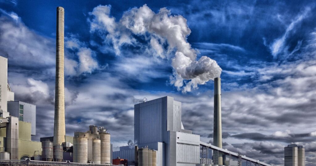 industrial zone, smokestacks releasing greenhouse gas into cloud covered sky