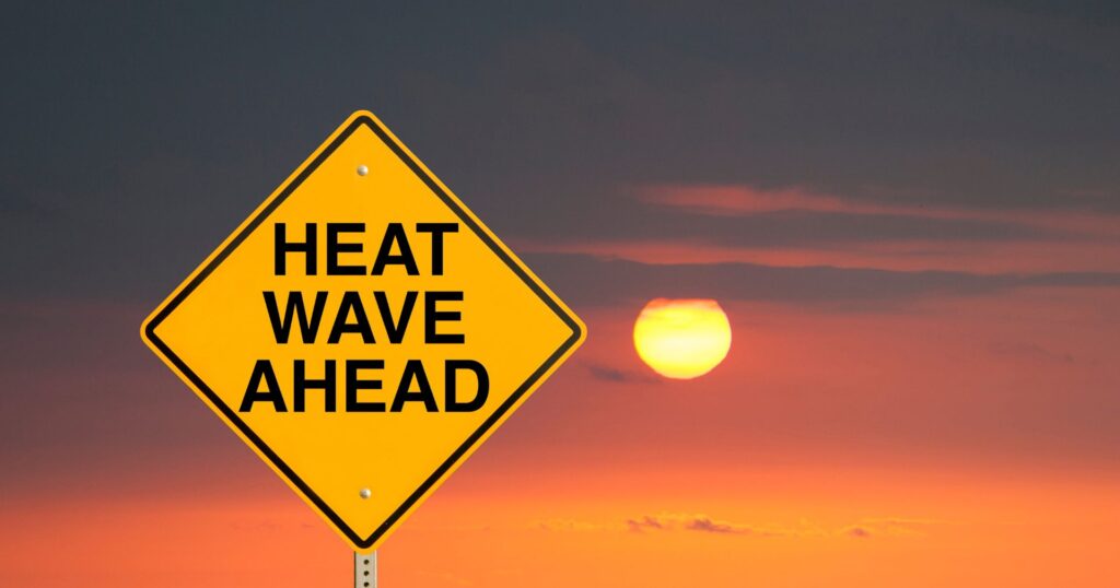 global heat wave ahead sign in front of setting sun